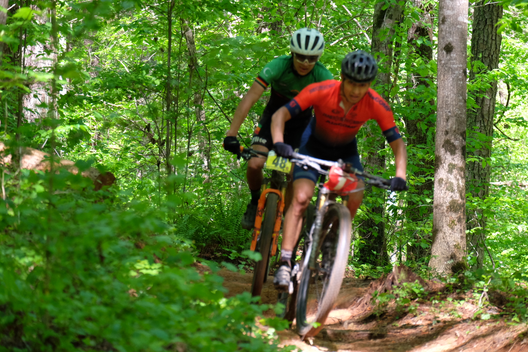 Douglas racing through a wooded singletrack section